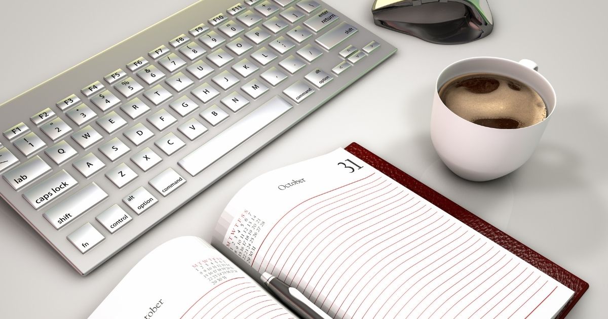 teclado de computadora y calendario con una taza de cafe